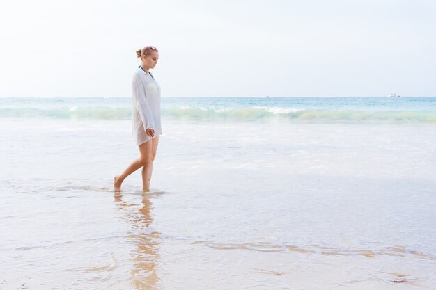 Fille se promène sur la plage et dans l'eau