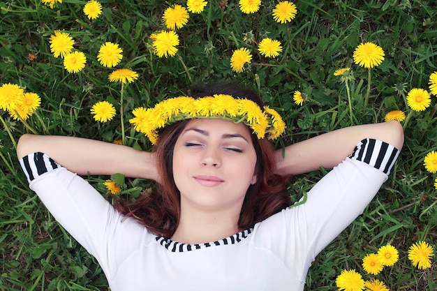 Photo fille se reposant par une journée ensoleillée dans un pré de pissenlits jaunes