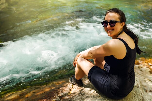 Fille se repose avec des rafraîchissements au bord de la rivière