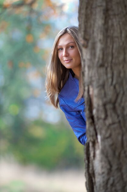 La fille se tient à la base d'un grand chêne