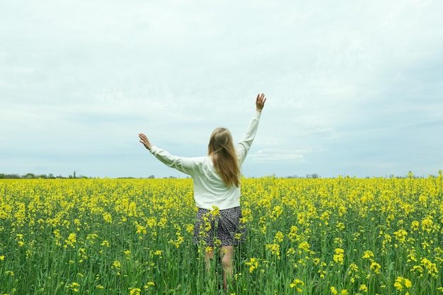 Une fille se tient dans un champ de colza un jour d'été