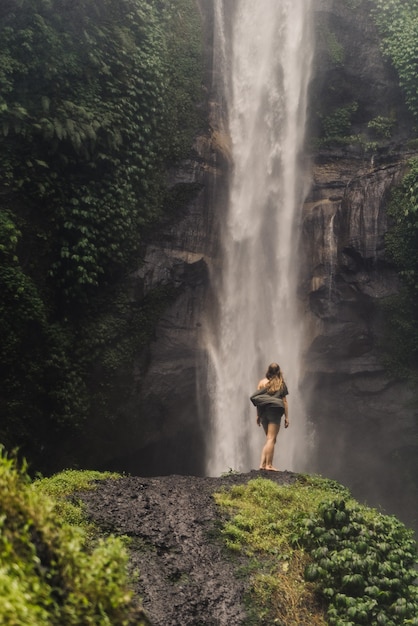 Fille se tient devant une énorme cascade