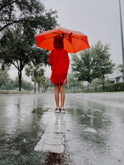 Une fille se tient avec un parapluie sous la pluie