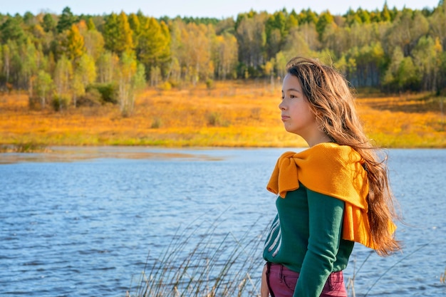 Une fille se tient près du lac La fille regarde la nature d'automne Les couleurs de la forêt d'automne et la fille