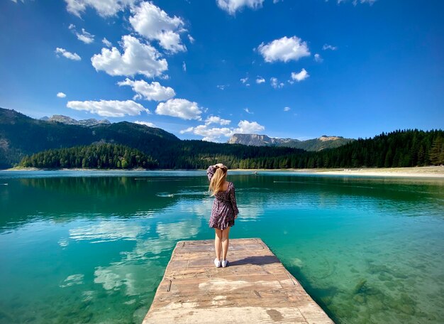 Une fille se tient sur un quai dans le lac dans les montagnes