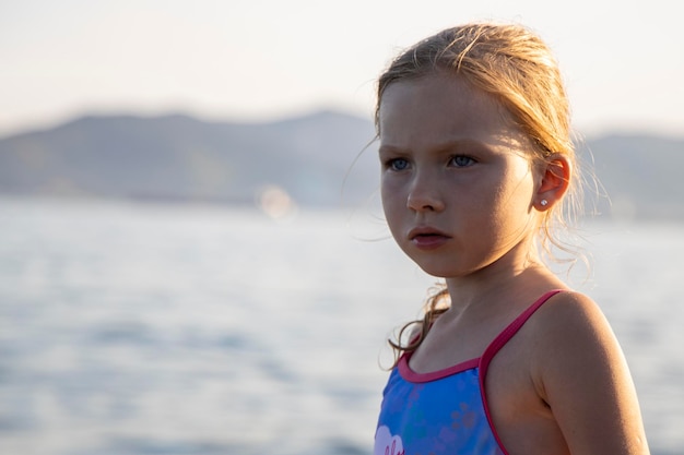 La fille se tient sur le rivage et la plage