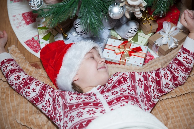 Une fille se trouve à l'arbre de Noël avec des cadeaux