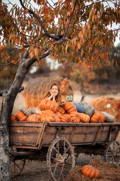 Une fille se trouve sur un chariot avec des citrouilles mûres