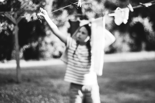 Une fille sèche des vêtements sur une corde à linge dans le jardin.