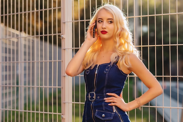 Photo fille séduisante blonde émotive à lunettes de soleil avec téléphone en été soleil urbain