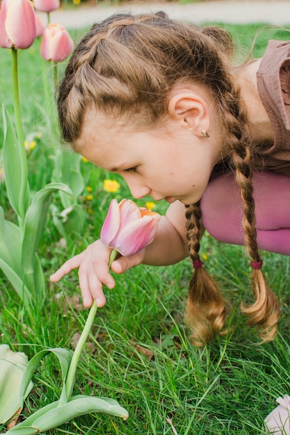 Fille sentant des fleurs dans le jardin