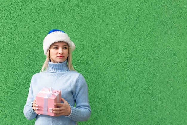 La fille sérieuse dans un chapeau de nouvel an avec un cadeau