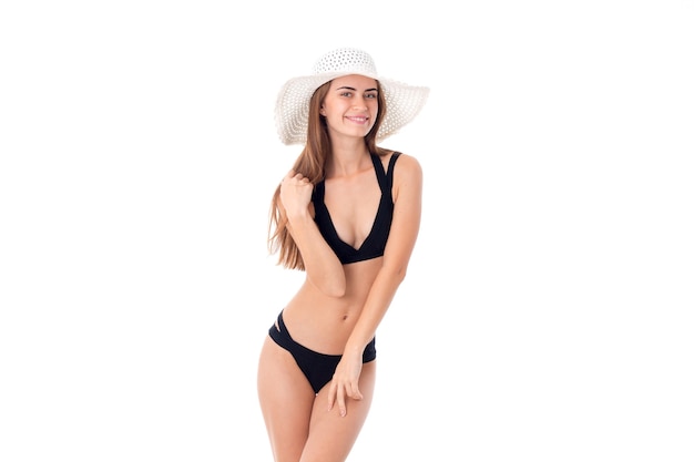 Fille sexuelle en maillot de bain noir et chapeau blanc à large bord isolé en studio