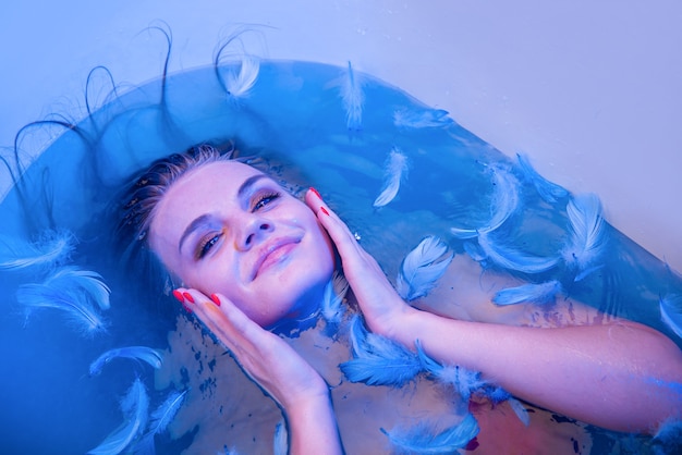 Fille sexy dans le bain spa heure du bain lavage du corps soins des cheveux néons néon spa concepts plumes dans