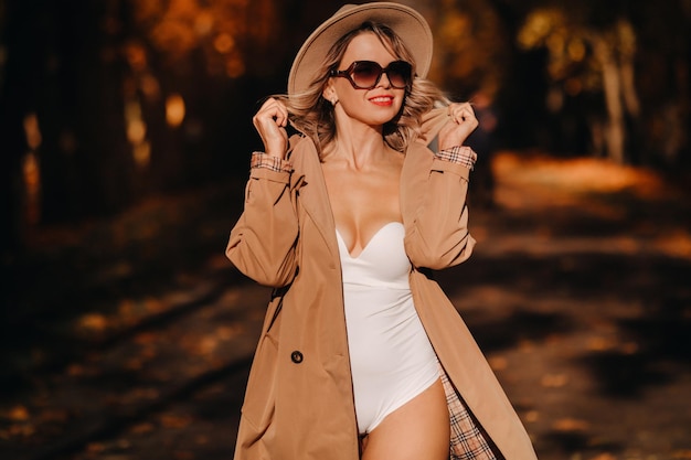 Fille sexy dans un manteau et un chapeau dans un parc ensoleillé d'automne