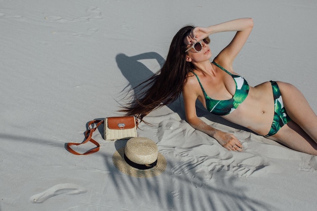 Fille sexy dans le sable en bikini blanc