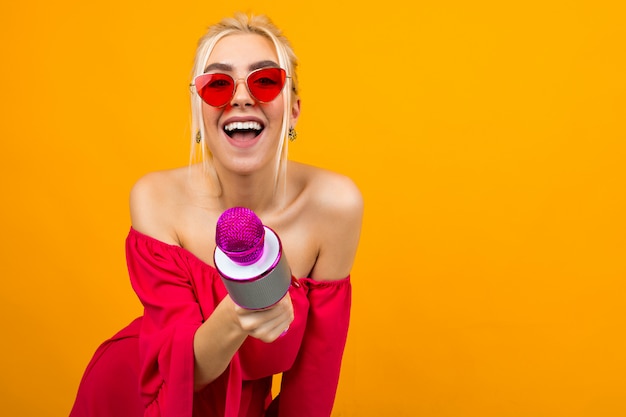 Photo fille sexy européenne menant l'événement dans une robe rouge aux épaules nues avec un microphone dans ses mains