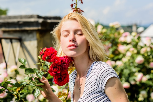 Fille sexy avec une rose rouge. belle femme aux cheveux blonds dans le jardin. beauté naturelle. Spa et soins de la peau. nature du parc d'été et de printemps. odeur de fleur de rose. Parfumer. détente le matin.