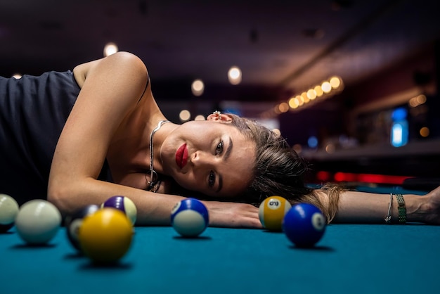 Une fille sexy se trouve sur la table de billard parmi les boules
