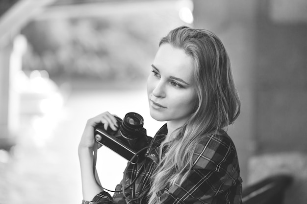 Fille en short et chemise rouge dans une cage, avec un appareil photo rétro dans les mains