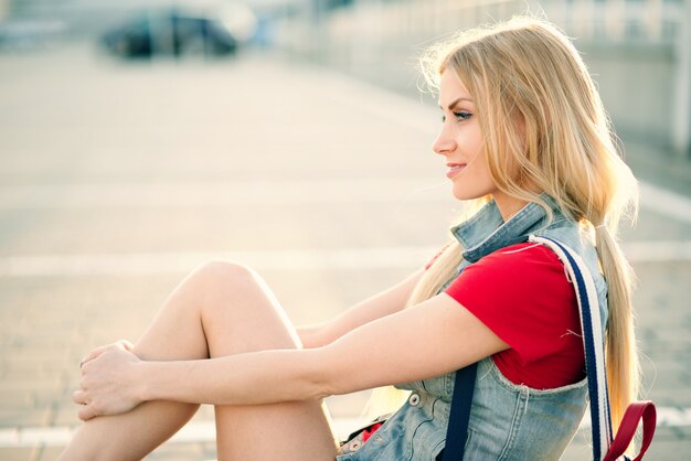 fille en short et nattes est assise sur le sol en été dans la ville