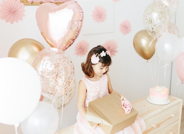 Fille de six ans portant une robe rose clair célébrant son anniversaire à la maison