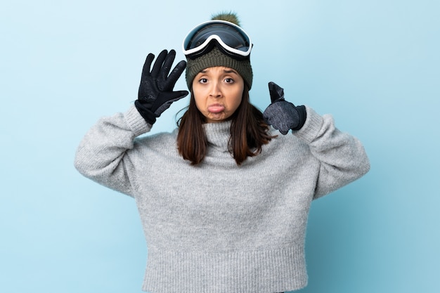 Fille De Skieur De Race Mixte Avec Des Lunettes De Snowboard Sur Mur Bleu Comptant Six Avec Les Doigts