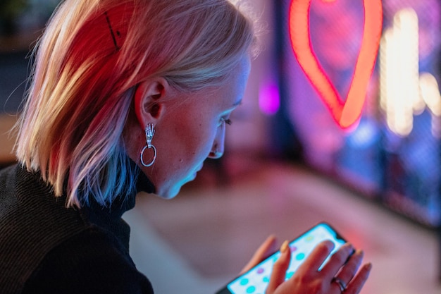 fille avec smartphone sur fond néon