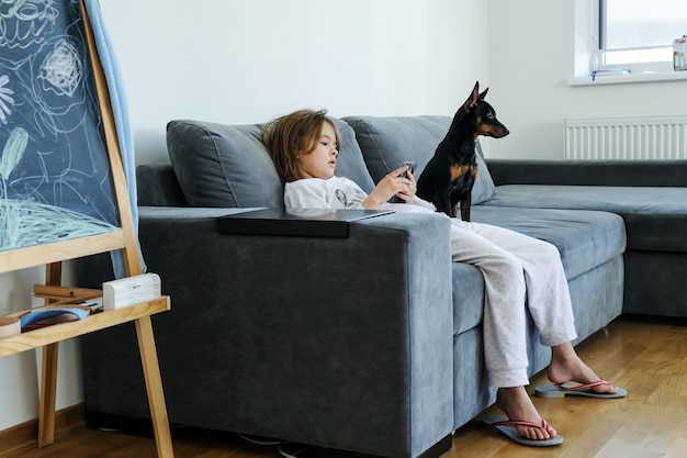 La fille avec un smartphone regarde l'écran. Il y a un chien près d'elle.