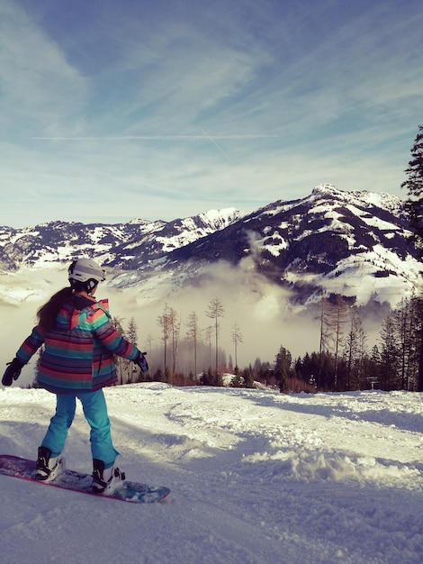 Photo fille en snowboard sur un champ couvert de neige contre le ciel