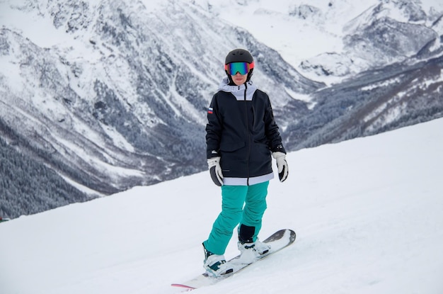 Une fille en snowboard descend le flanc de la montagne