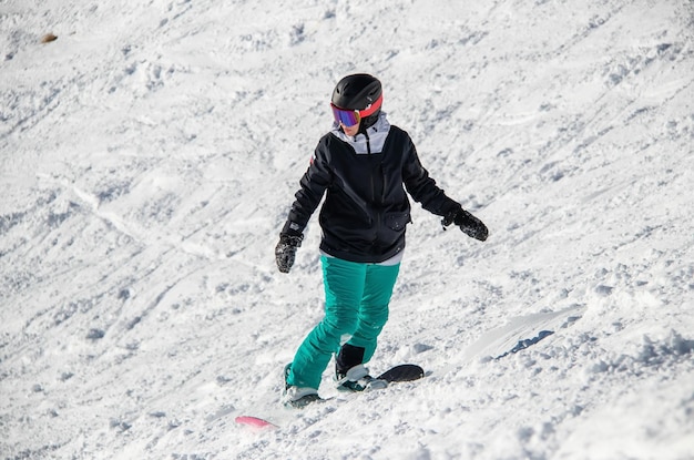 Une fille en snowboard descend le flanc de la montagne