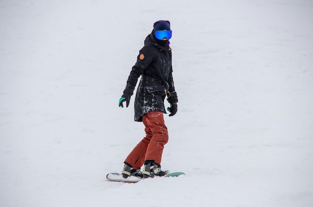 Photo une fille sur un snowboard descend le flanc de la montagne