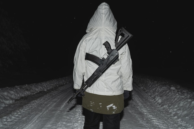 Photo une fille soldat en camouflage d'hiver avec un fusil d'assaut ak-12 derrière son dos vue de l'arrière