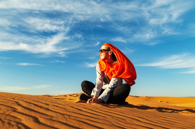 Fille solitaire dans le désert du Sahara au coucher du soleil. Erg Chebbi, Merzouga, Maroc.