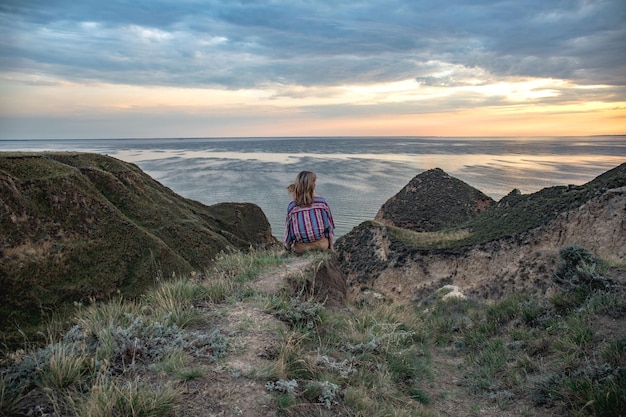 Fille solitaire regardant un beau coucher de soleil sur une colline