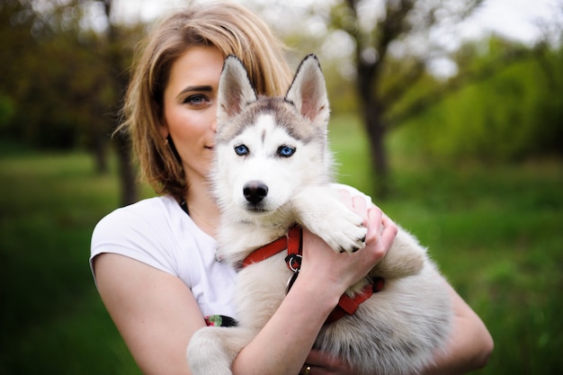 Une fille et son chien husky marchant dans un parc.