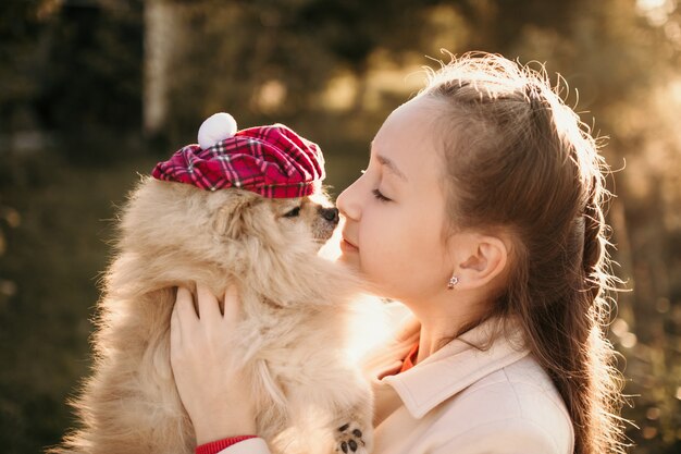 Une fille avec son chien de Poméranie dans un béret à carreaux pour une promenade dans l'après-midi d'automne