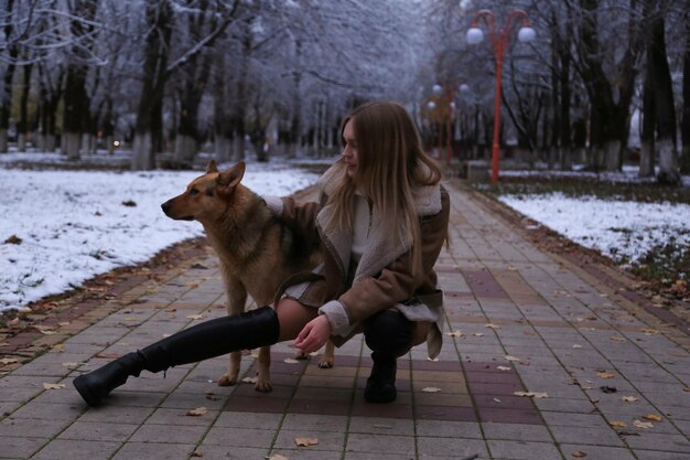 une fille et son chien sont sur un trottoir dans la neige