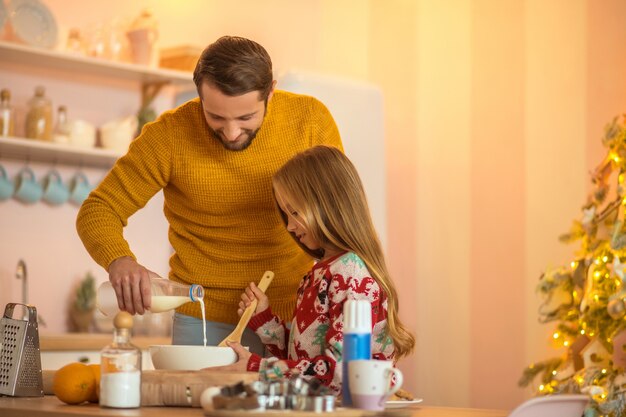 Fille et son père en remuant quelque chose dans un bol et souriant