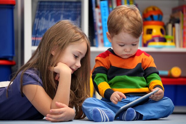 Fille avec son petit frère amusant à l'aide d'un ordinateur tablette numérique