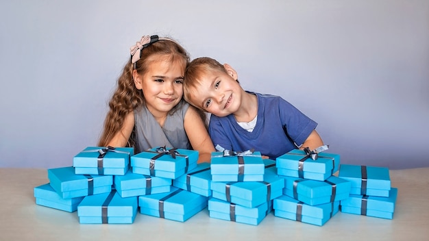 Fille avec son petit frère près d'une énorme pile de coffrets cadeaux