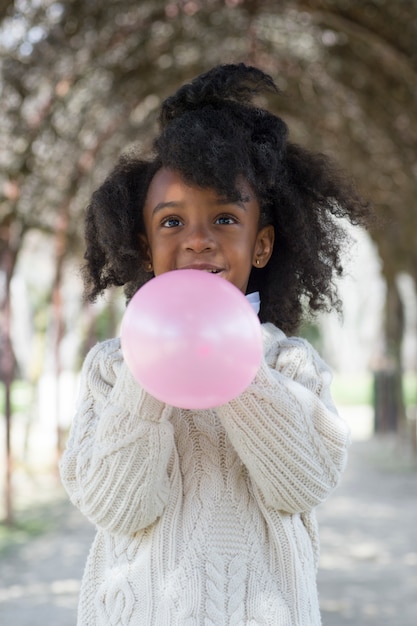 Fille soufflant un ballon à l'extérieur