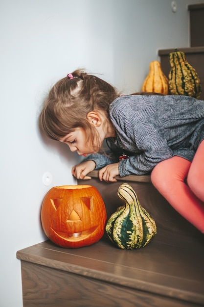 Fille soufflant à la bougie à l'intérieur de la citrouille d'Halloween