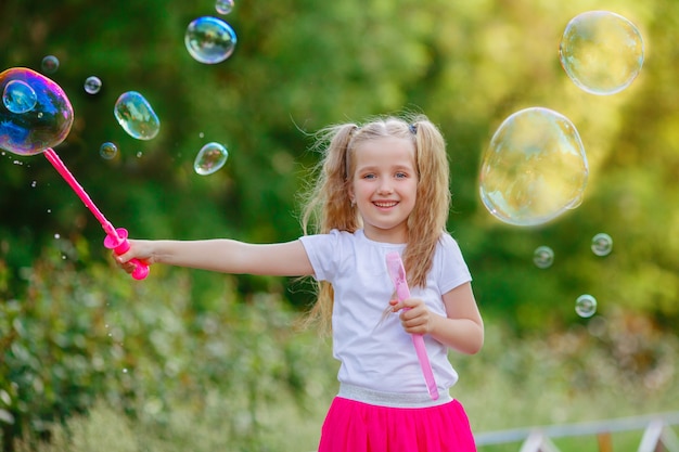 Une fille souffle des bulles de savon dans le parc en été