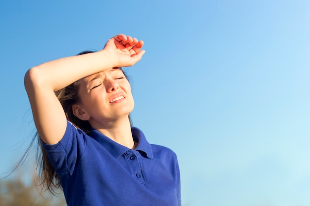 Fille souffrant de douleur, de chaleur, de femme avec un coup de chaleur. Avoir des insolations par temps chaud d'été. Soleil dangereux, fille sous le soleil. Maux de tête, se sentir mal. Personne tient la main sur la tête.