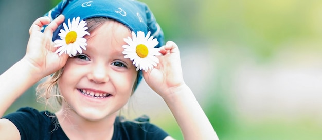 une fille souriant à la caméra avec des marguerites dans les mains