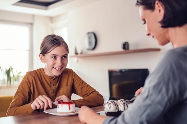 Fille souriant et mangeant un gâteau au fromage avec sa mère