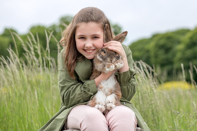 Fille souriante avec animal de compagnie, lapin au gingembre dans la nature