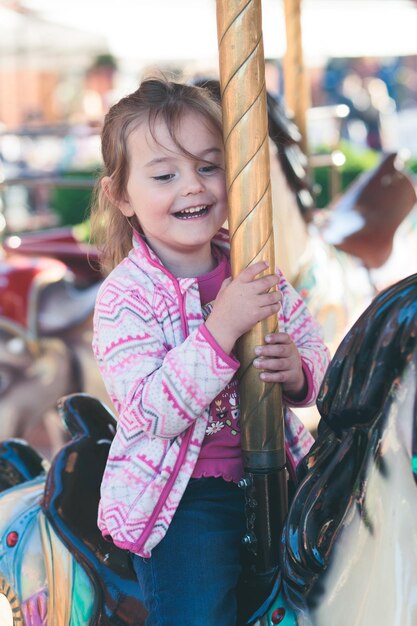Une fille souriante assise sur un carrousel